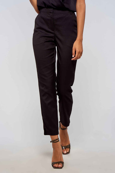 Zwarte broek van VERO MODA® met strakke pasvorm, lichte textuur en opgerolde pijpen, gedragen met hoge hakken.