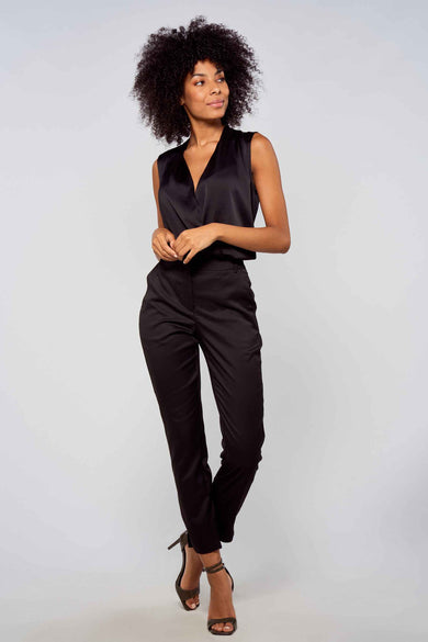 Zwarte broek van VERO MODA® met strakke pasvorm, gladde stof en opgerolde pijpen, gedragen met een zwarte mouwloze top en hoge hakken.
