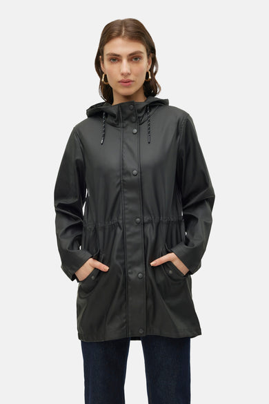 Zwarte regenjas van Vero Moda, met capuchon, knoopsluiting en steekzakken, gedragen over een donkere jeans.