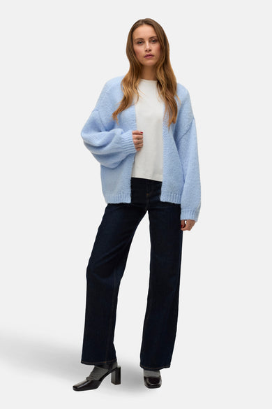 Blauw vest van VERO MODA, gedragen over een wit T-shirt en donkere spijkerbroek met hakken en sokken.
