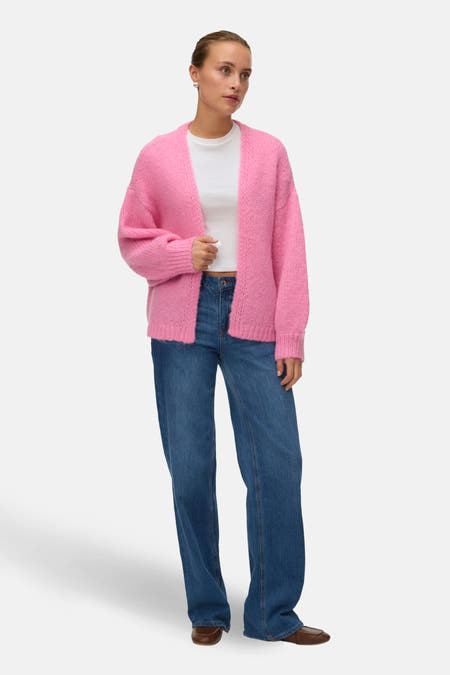 Roze vest van VERO MODA, gedragen over een wit shirt en blauwe jeans.