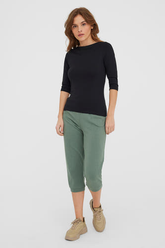Zwart T-shirt met lange mouwen van VERO MODA®, gedragen met groene driekwart broek en beige sneakers.