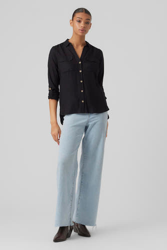 Chemise noire à manches longues de VERO MODA, avec des boutons dorés et portée avec un jean large et des bottines brunes.