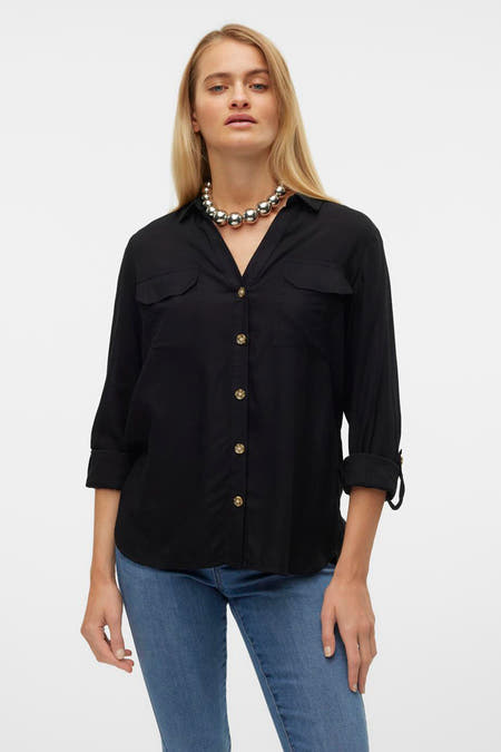 Zwart overhemd met lange mouwen van VERO MODA, met borstzakken, gouden knopen en een zilverkleurige halsketting.
