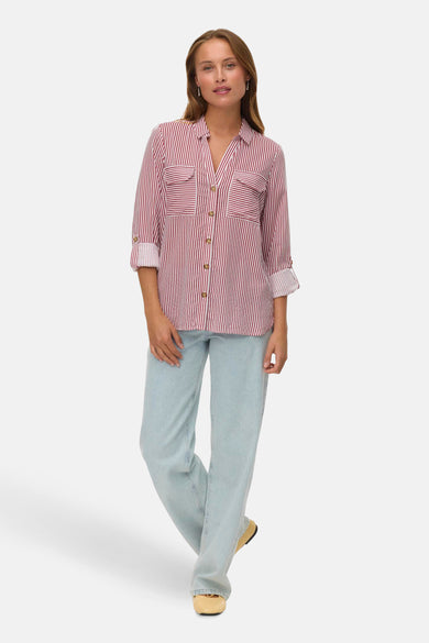 Chemise rayée rouge et blanche à manches longues de VERO MODA®, avec des manches retroussées, portée avec des jeans bleu clair et des chaussures beige.