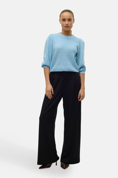 Blauwe trui met ronde hals van Vero Moda, met pofmouwen en gedragen met zwarte, wijd uitlopende broek.
