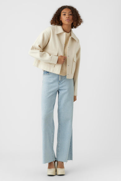 Beige korte jas van VERO MODA® met knopen en zakken, gedragen met lichtblauwe jeans en witte platform schoenen, front view