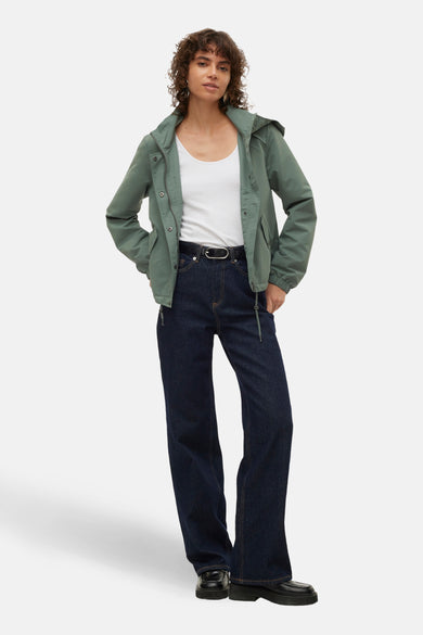 Korte groene jas van VERO MODA, met een capuchon, gedragen met een wit shirt en een donkere broek.