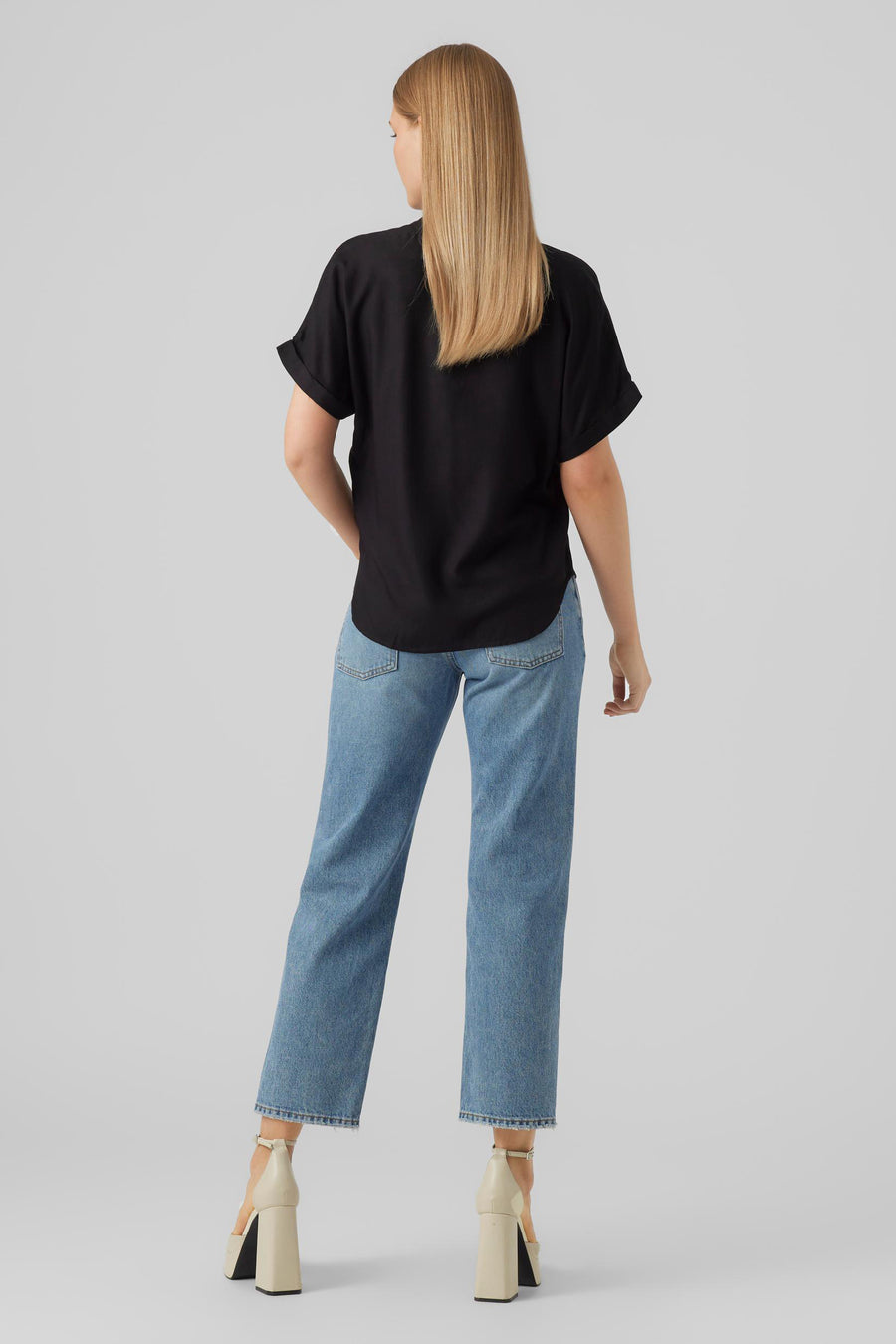 Chemisier noir à manches courtes de VERO MODA, vu de dos, associé à un jean et des talons beiges.