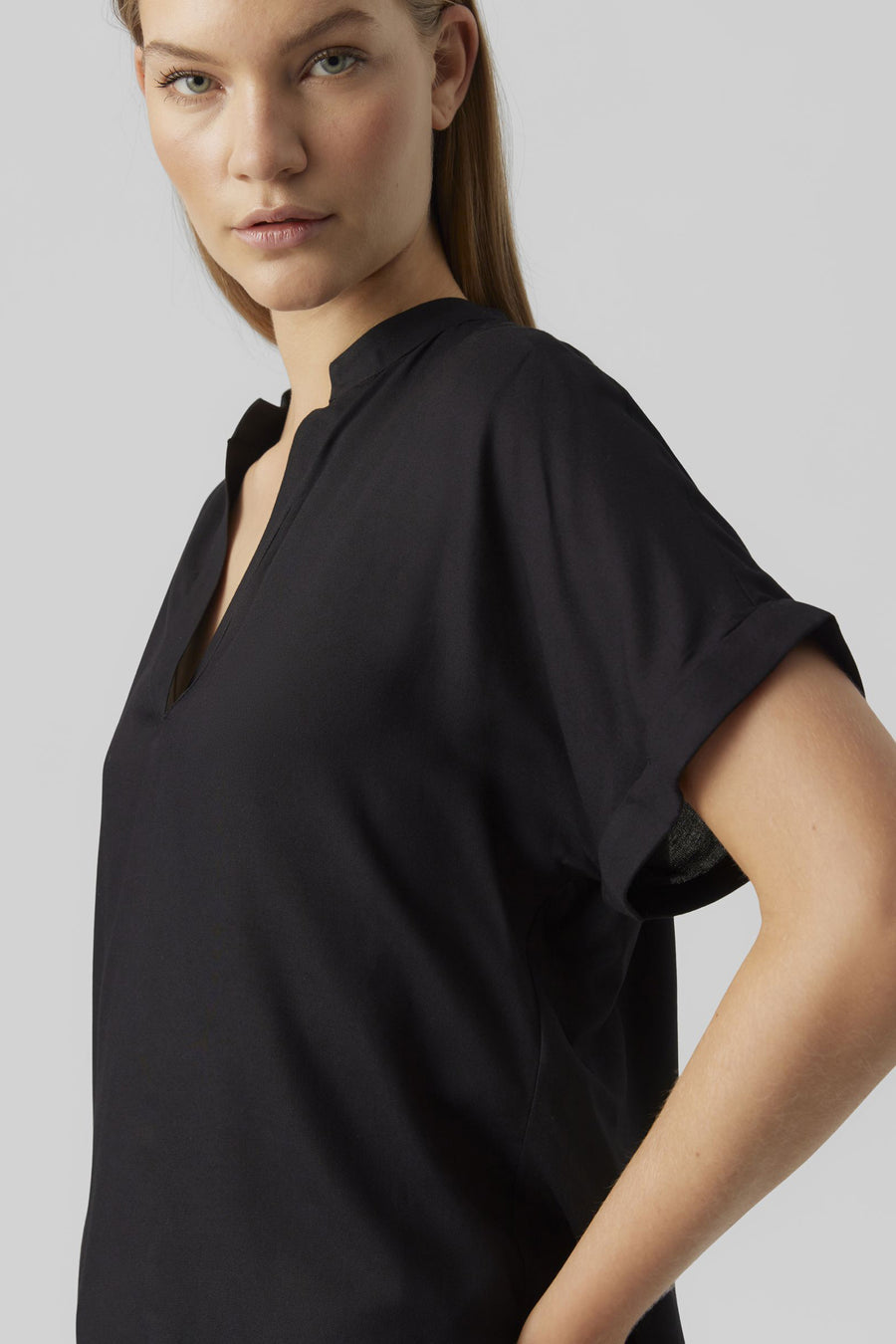 Chemisier noir à manches courtes de VERO MODA, avec un col en V et porté avec un jean bleu.