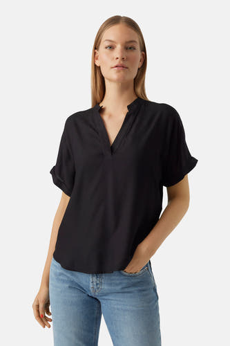 Zwarte blouse met korte mouwen van VERO MODA, met een V-hals en gedragen met een blauwe jeans.

