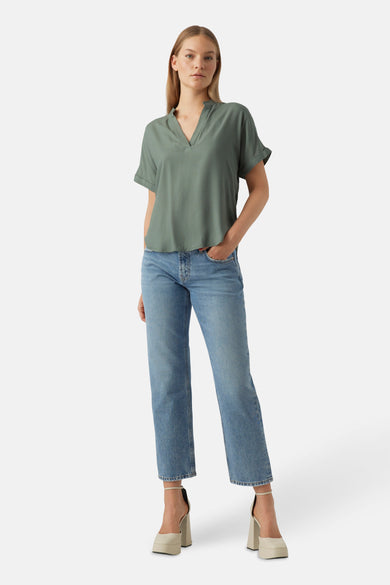 Groene blouse met korte mouwen van Vero Moda, gecombineerd met jeans en beige plateau pumps.
