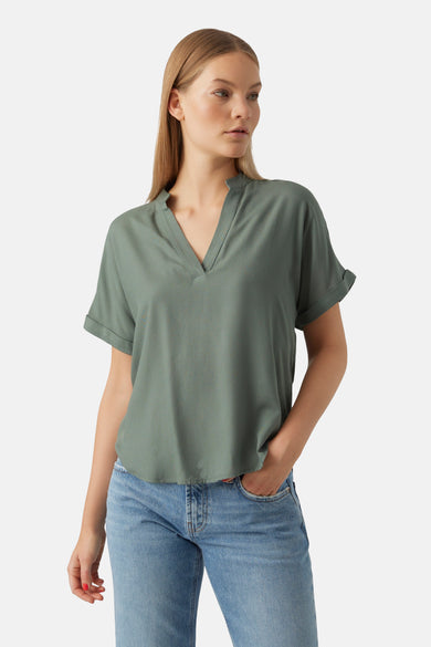 Groene blouse met korte mouwen van VERO MODA, met een V-hals en gerolde mouwen, gecombineerd met blauwe jeans.
