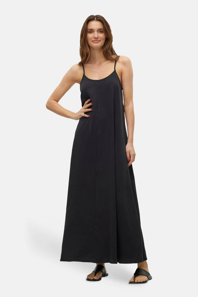 Zwarte mouwloze kleedje van VERO MODA, in een losse stijl, gedragen door een model met sandalen.
