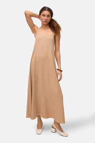 Beige kleedje zonder mouwen van Vero Moda, met een houten armband en crèmekleurige schoenen.
