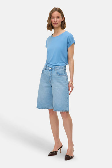 T-shirt bleu à manches courtes de VERO MODA, porté avec des shorts en denim et des mocassins bruns.