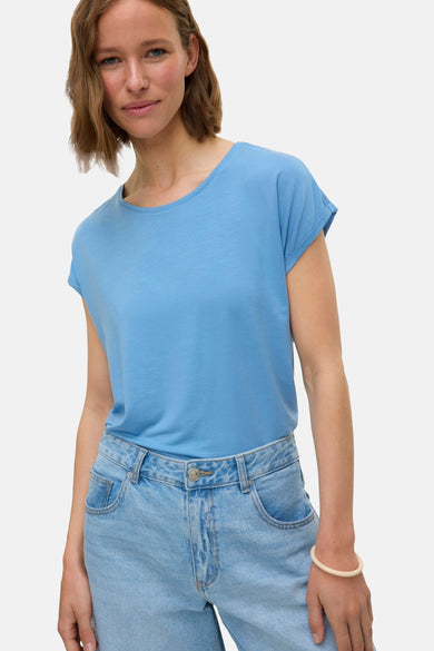 T-shirt bleu à manches courtes de VERO MODA®, porté avec un jean et un bracelet.