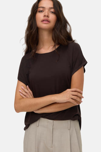 Bruin T-shirt met korte mouwen van VERO MODA, gedragen met een beige pantalon en gekruiste armen.