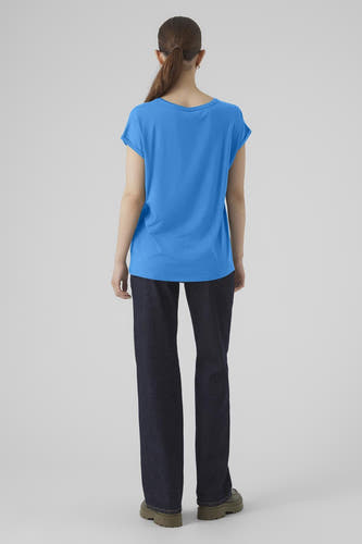 T-shirt bleu à manches courtes de VERO MODA, avec une coupe décontractée, porté avec des jeans foncés et des chaussures vertes.