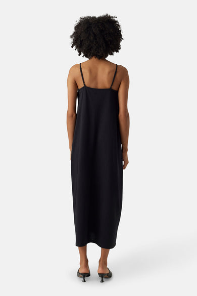 Jupe sans manches noire de VERO MODA, vue de derrière, avec des fines bretelles et des talons.