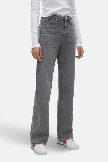 Grijze wijde jeans van VERO MODA, met een middelhoge taille en gecombineerd met een wit shirt en witte sneakers.