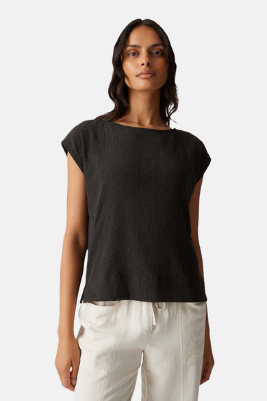 Bruine mouwloze blouse van OPUS, met een subtiele textuur en gedragen met een lichte broek.
