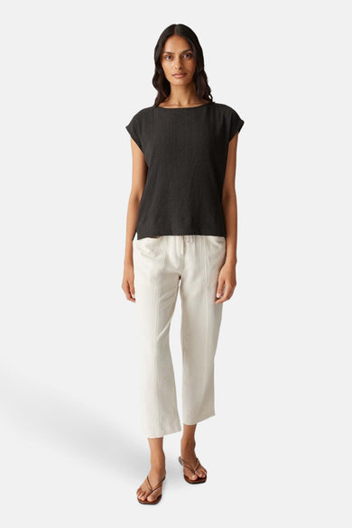 Bruine mouwloze blouse van OPUS, met een subtiele textuur en gecombineerd met een crèmekleurige broek.
