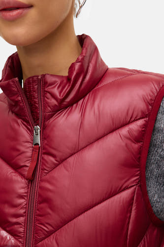 Gilet rouge de VERO MODA, avec des coutures diagonales et une fermeture éclair argentée visible.