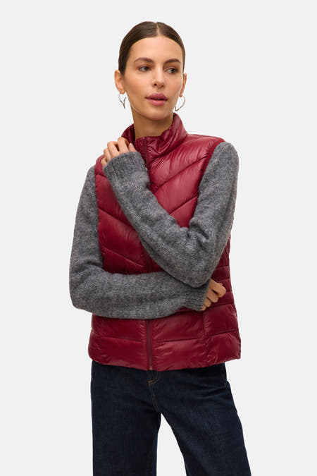 Rode bodywarmer van VERO MODA, met een gewatteerd patroon, gedragen over een grijze trui en donkere jeans.