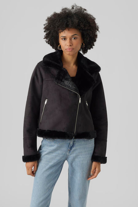 Zwarte korte jas van VERO MODA, met imitatiebont aan de kraag, manchetten en zoom, gedragen met een spijkerbroek.
