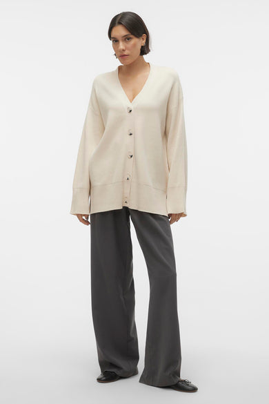 Beige gilet van VERO MODA®, gedragen over grijze broeken en zwarte schoenen.
