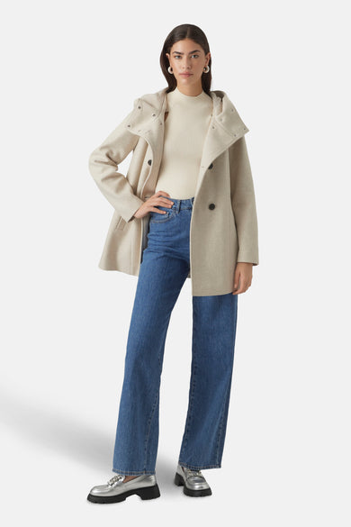 Beige korte jas van VERO MODA®, met capuchon, gecombineerd met een gebreide top en jeans.