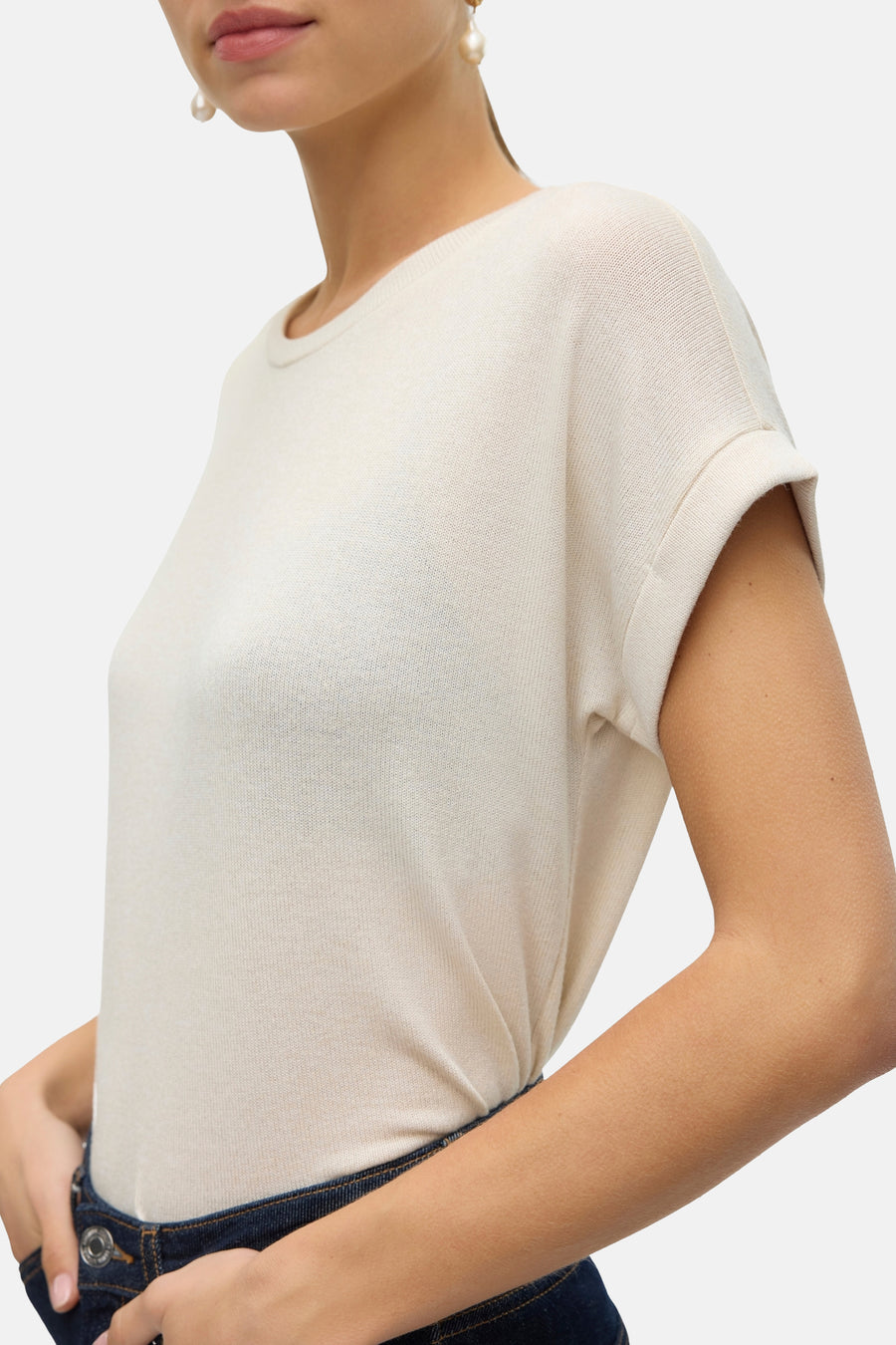 Beige T-shirt met korte mouwen van VERO MODA, met opgerolde mouwen, gedragen met een donkerblauwe jeans.
