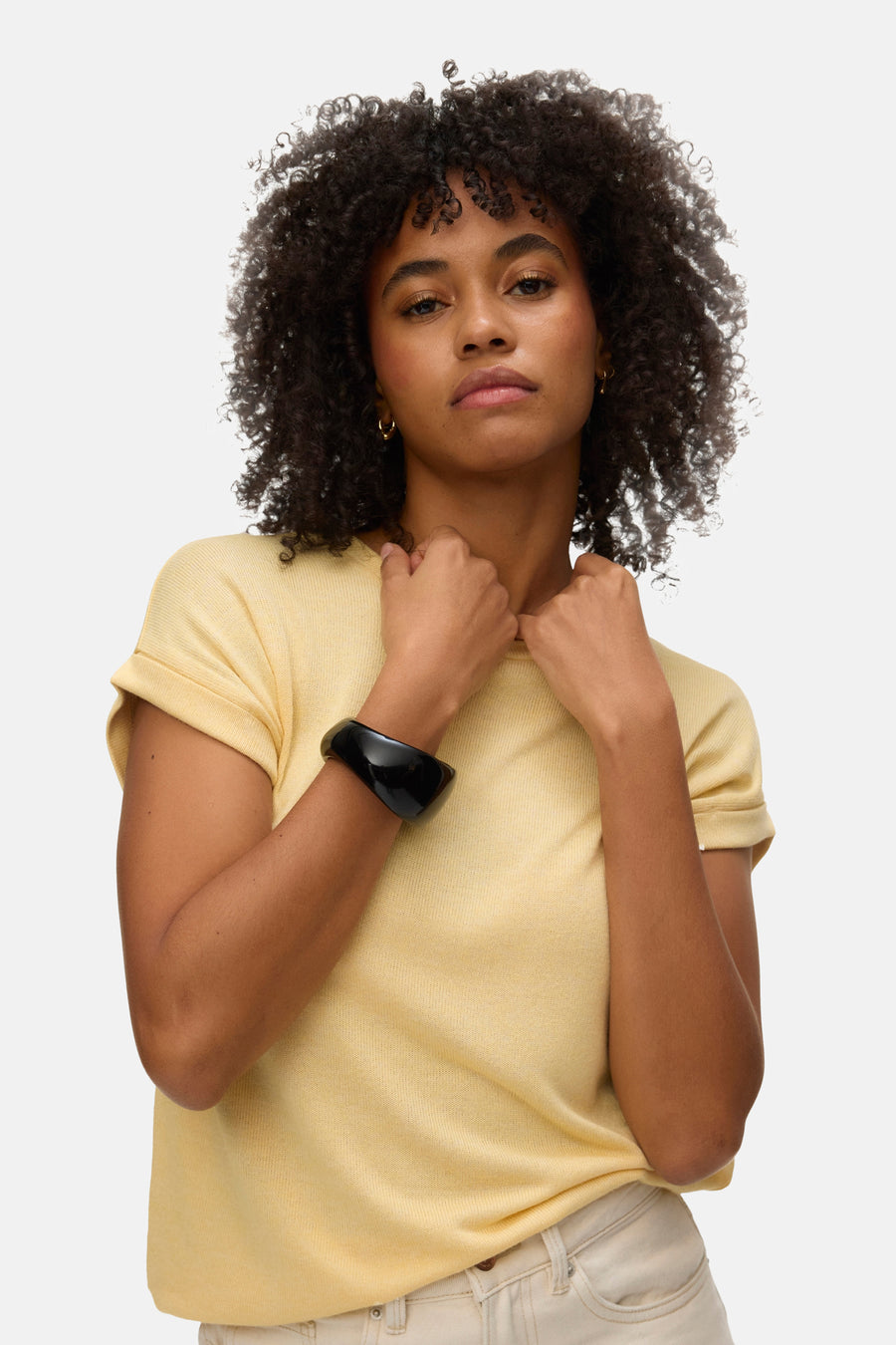 Geel T-shirt met korte mouwen van VERO MODA®, gedragen met een zwarte armband en lichte jeans.