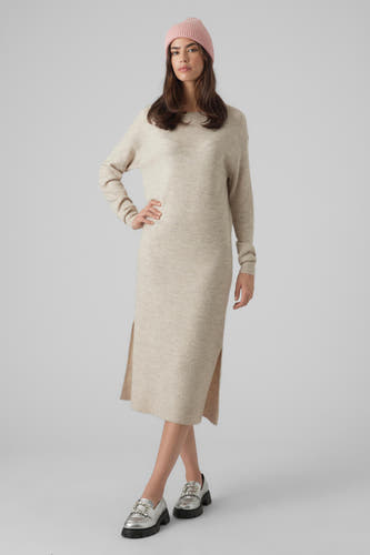 Beige kleedje met lange mouwen van Vero Moda, met zijsplit en gecombineerd met zilveren loafers en een roze beanie.
