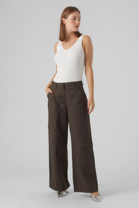 Groene broek van VERO MODA, met wijde pijpen en cargo zakken, gecombineerd met een witte top en zilverkleurige pumps.
