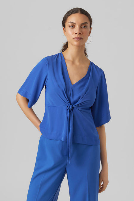 Blauwe blouse met driekwart mouwen van VERO MODA, geknoopt aan de voorkant, gedragen met bijpassende broek.