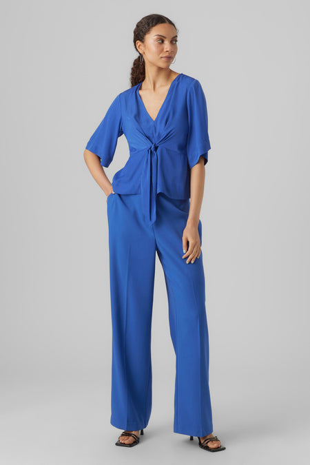 Blauwe blouse met driekwart mouwen van VERO MODA, met een knoopdetail en gecombineerd met een bijpassende broek en hakken.
