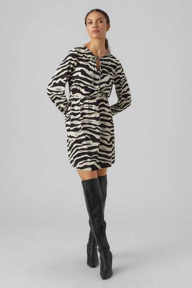 Jupe courte avec des manches longues de VERO MODA, imprimé zèbre et associée à des bottes noires hautes.