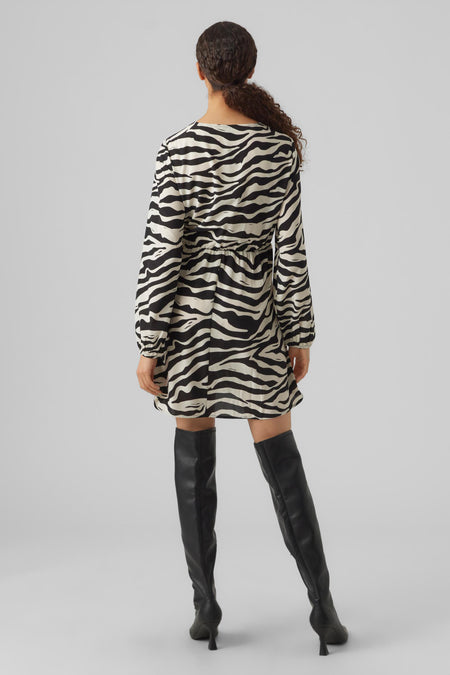 Jupe courte à imprimé zèbre de VERO MODA, avec des manches longues et associée à des bottes genouillères noires.