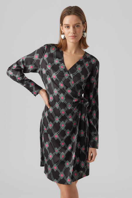 Zwarte korte jurk van VERO MODA, met roze en groene ruitpatroon, lange mouwen en hartvormige oorbellen.
