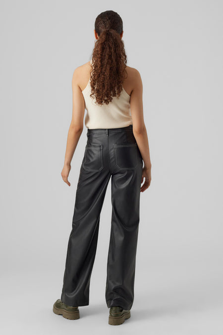 Pantalon cargo noir de VERO MODA, avec des boutons décoratifs, associé à une chemise blanche et à des chaussures vertes.