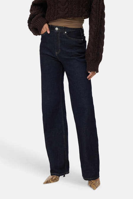 Donkere blauwe wijde jeans van VERO MODA®, met hoge taille en goudkleurige naden, gedragen met een gebreide trui en slangenprint schoenen.