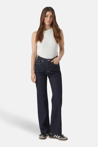 Jean large en denim bleu foncé de VERO MODA, avec une chemise blanche à fines rayures et des baskets Adidas.
