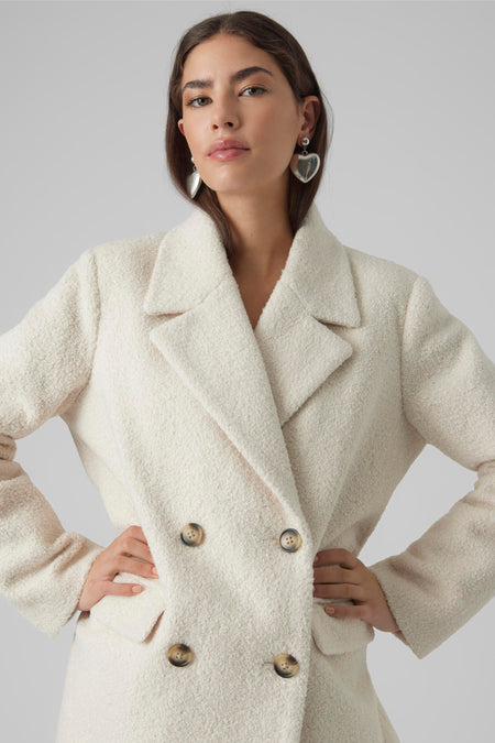 Ecru korte jas van VERO MODA® met dubbele rij donkere knopen en geborstelde textuur, vooraanzicht model met handen op heupen