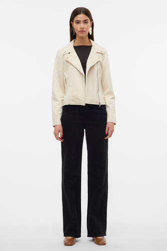 Manteau beige de VERO MODA, avec une fermeture éclair asymétrique et porté avec un pantalon noir et des chaussures marron.