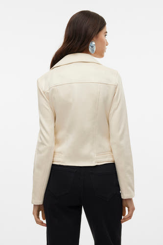 Manteau beige de VERO MODA, avec des manches longues, vu de derrière, associé à des jeans noirs et de grandes boucles d'oreilles.