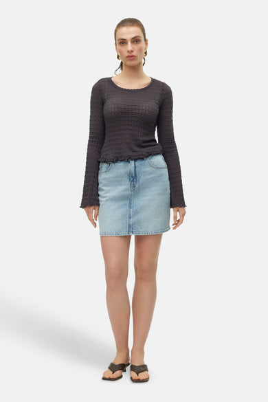 Lichtblauwe denim korte rok van VERO MODA® met high-waist, gestyled met een getextureerde donkergrijze top en bruine teenslippers.