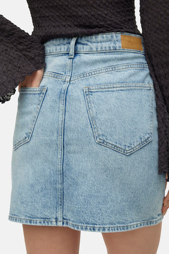 Jupe courte en denim bleu clair de VERO MODA® avec poches arrière, passants de ceinture et un haut en tricot gaufré foncé.