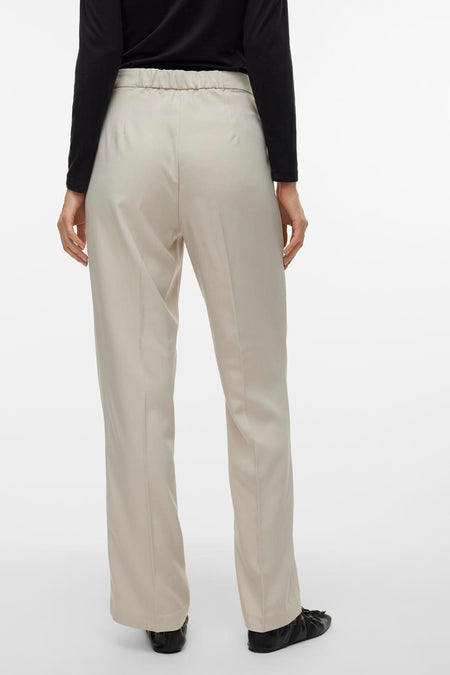 Beige broek van VERO MODA, gezien van achteren, gecombineerd met een zwarte top en zwarte platte schoenen.